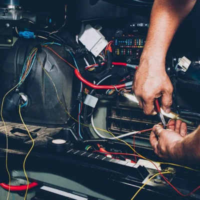 Technician using multimeter to trace car electrical issues